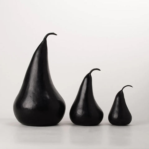 Three black pear-shaped marble objects on a light gray background