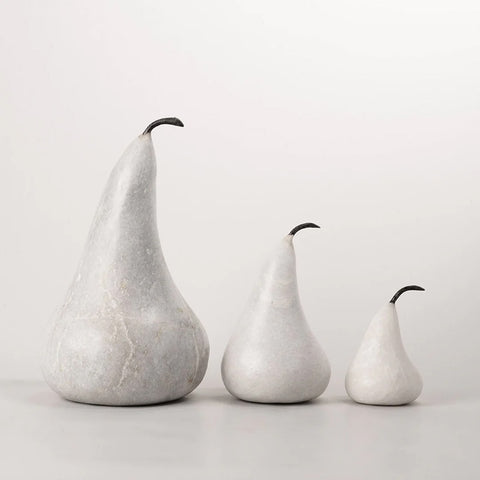 Three marble pear-shaped sculptures of different sizes on a light gray background