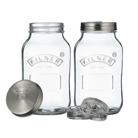 Two glass jars with metal lids containing pickled vegetables on a white background