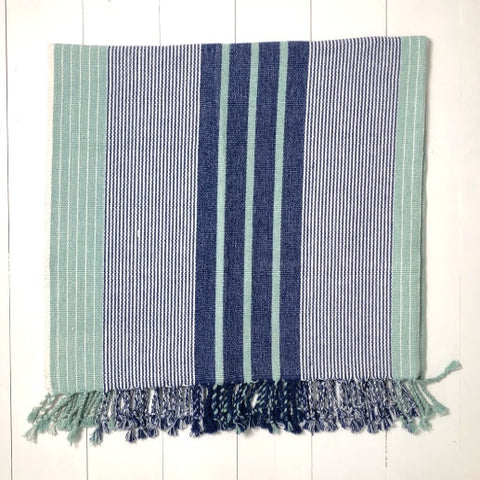 Striped towel with blue and green colors on a white wooden surface