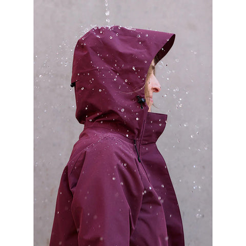 Woman wearing a burgundy raincoat on a white background