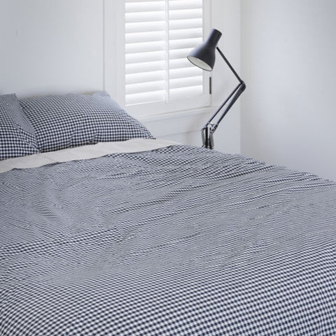 Stack of navy and white checkered bedding on a white background