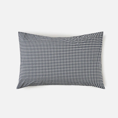 Navy and white checkered bedding with beige comforter on a bed.