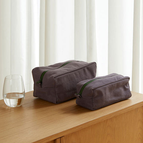 Two purple toiletry bags with green zippers on a white background