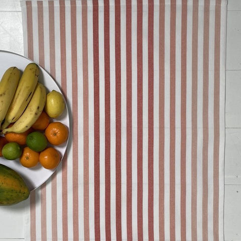 A green and white striped cotton tea towel displayed with lemons on top.