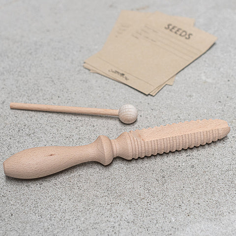 Wooden seed chute in a cardboard packaging with branding and product description on a gray background