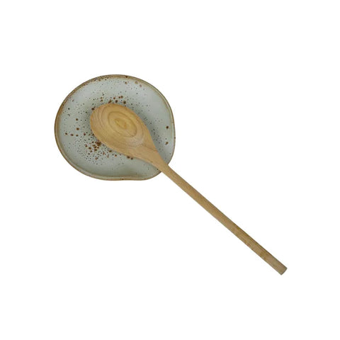 Round ceramic spoon rest with speckled design on a white background