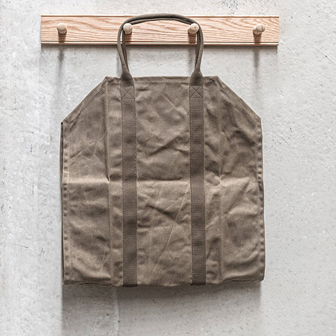 person holds a Waxed Canvas Log Carrier by Heaven In Earth filled with flowers