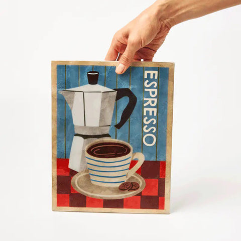 Red espresso maker next to a decorative sign with coffee-themed illustration on a light blue background.
