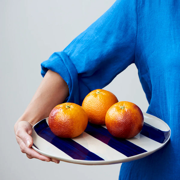 Cabana Stripe Platter in Blue with oranges by Jones & Co held by person in blue shirt 