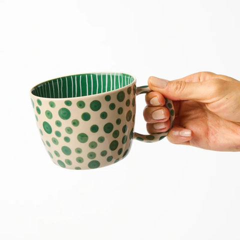 Mug with green polka dot pattern on a white background