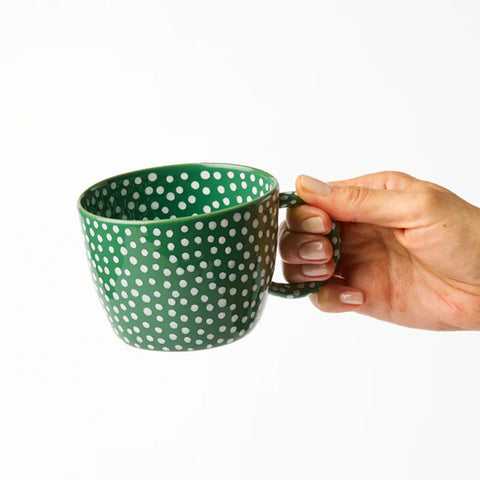 Green mug with white polka dots on a white background