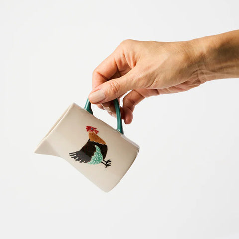 Ceramic pitcher with a rooster design on a white background