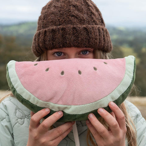A plush watermelon slice cushion with a pink center, green rind, and embroidered seed details, shown on a plain white background.
