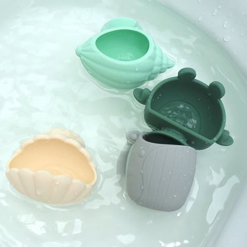 Set of four colorful silicone cups in a bathtub filled with water