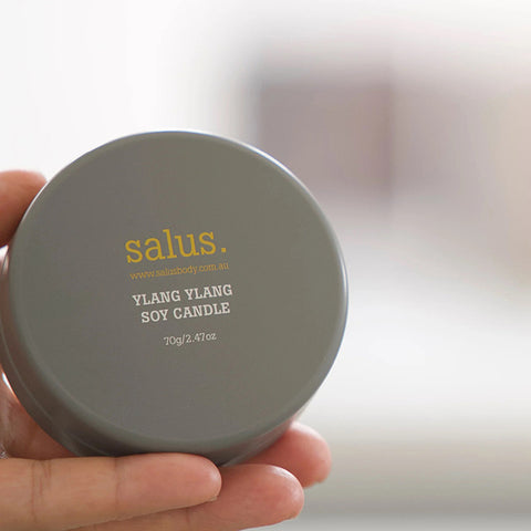 Stacks of gray and white small candles with 'salus' branding on a marble surface