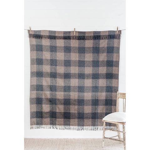 The Recycled Wool Check Blanket in Ash by The Grampians Goods Co hangs from a ladder near a fence