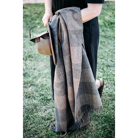 The Recycled Wool Check Blanket in Ash by The Grampians Goods Co hangs from a ladder near a fence