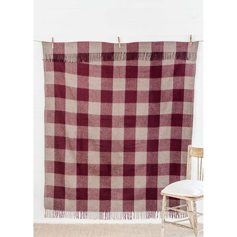 The Recycled Wool Check Blanket in Shiraz by The Grampians Goods Co hangs from a ladder near a fence