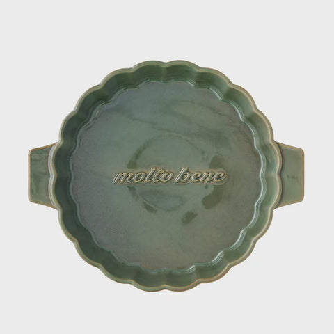 Green ceramic dish with scalloped edge and 'molto bene' branding on a light gray background
