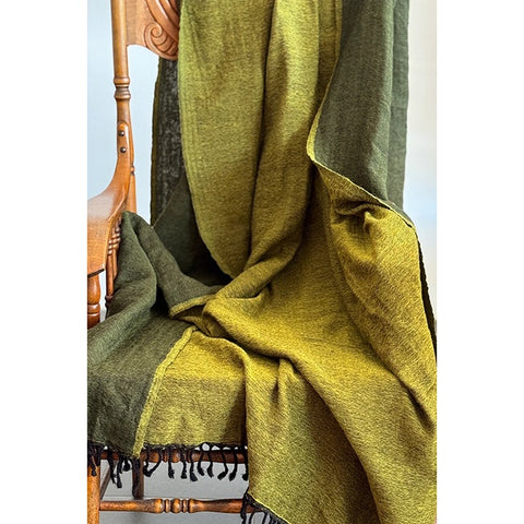 Green blanket draped over a chair in a room with floral wallpaper.